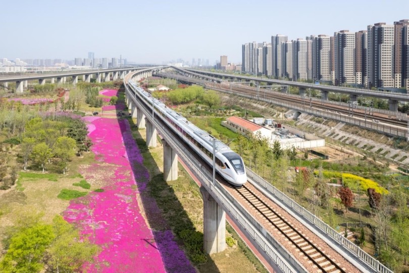 รถไฟจีนวิ่งผ่านทุ่งดอกไม้ในฤดูใบไม้ผลิ